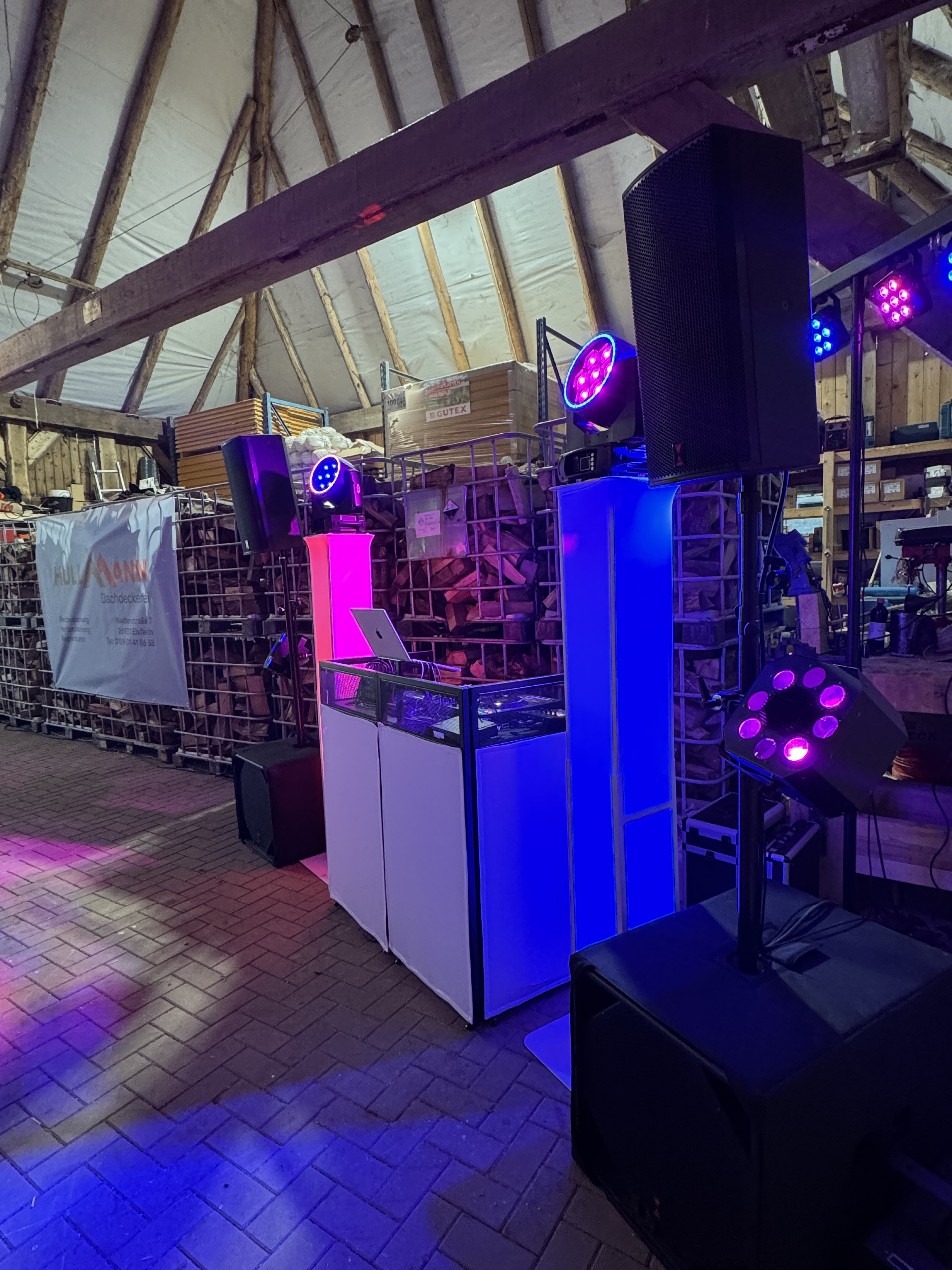 DJ-Setup in einer rustikalen Location mit blau-pinkem Licht